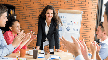 a confident woman receiving applause from team