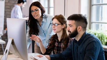 a group of professionals looking at a monitor