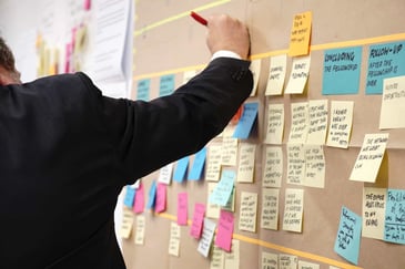 man putting notes on his vision board